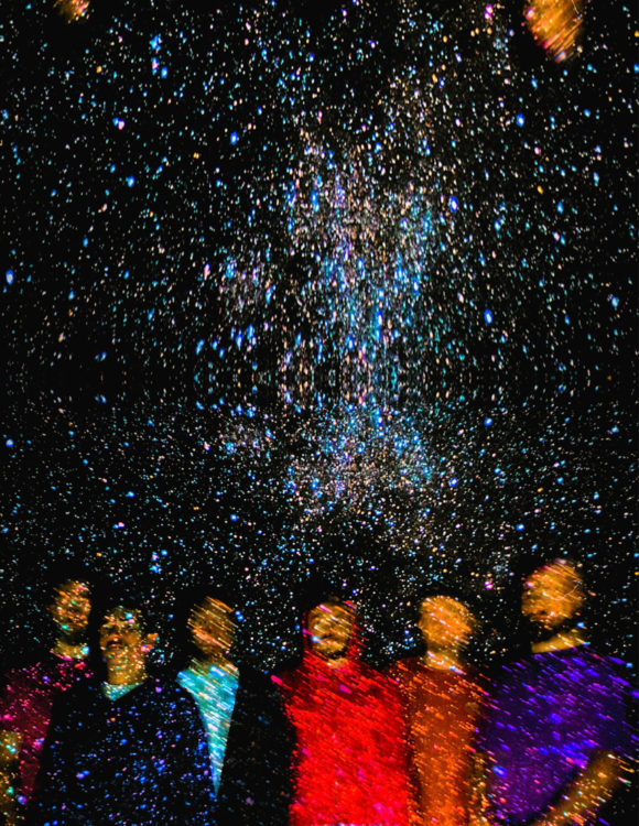 Photo de six garçons sur fond étoilé. Les musiciens sont flous